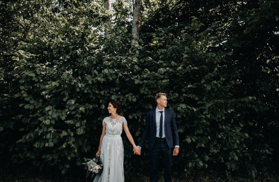 alyvų krūmas jaunieji kostiumas suknelė nuotaka puokštė fotosesija vestuvės fotografas susikibę už rankų