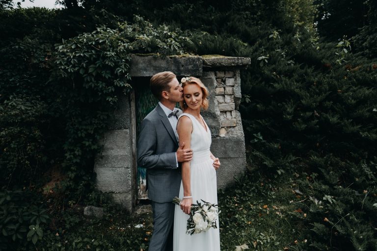 jaunieji santuoka vijokliai fotografas lapai siena akmenys puokštė nuotaka kostiumas suknelė boho rustic fotosesija sodas